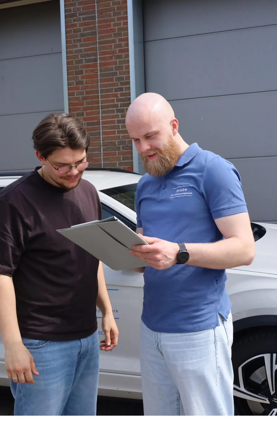 Kfz-Sachverständiger Alex Wiebe bespricht Unfallgutachten mit Kunde am Fahrzeug in Minden